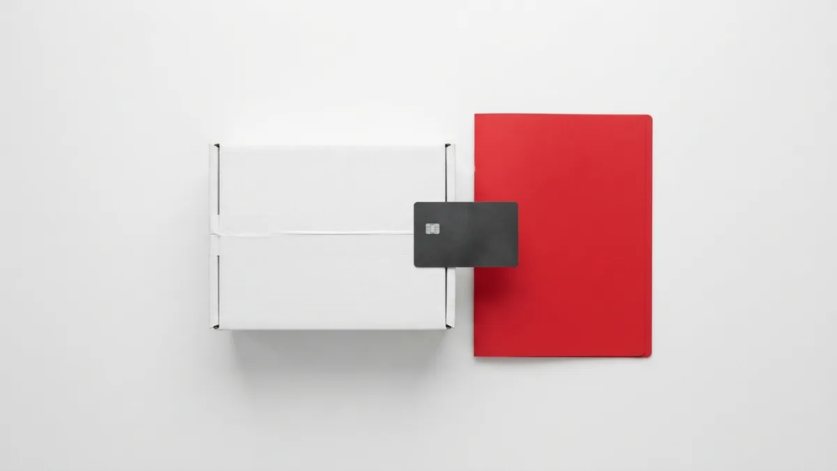 Payment and shipping setup White parcel and graphite payment card beside a crimson red folder