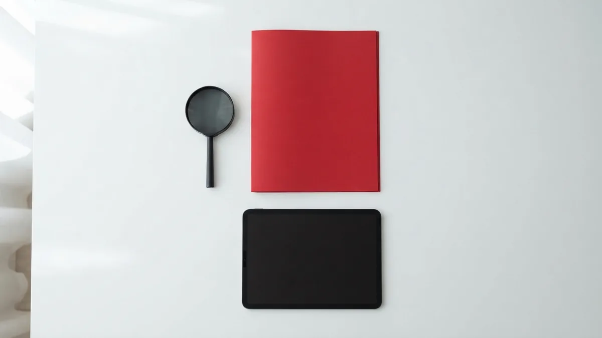 Graphite magnifier and crimson folder on a clean desk for checking website source clues