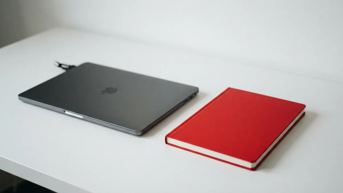 A calm workspace for theme research Graphite laptop and vivid red notebook on a clean white desk for researching a website theme