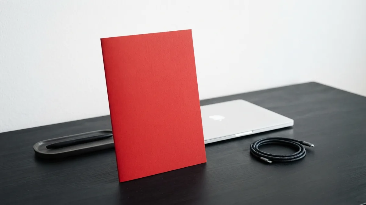Vivid red folder and white laptop arranged on a minimal desk for planning a WordPress page layout