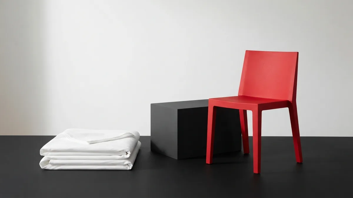 White fabric and graphite display block beside a crimson chair for store design